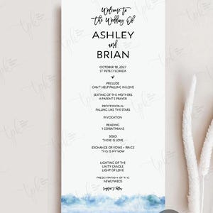 May include: A vertical wedding program card featuring black text on a white background with a watercolor ocean wave illustration at the bottom. The text includes "Welcome to the Wedding Of ASHLEY and BRIAN" and a detailed ceremony order of events.