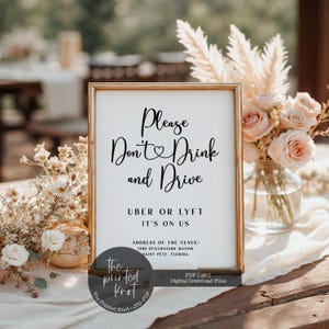 Può includere: Un cartello incorniciato con la scritta "Please Don't Drink and Drive" in elegante corsivo. Il cartello include anche "Uber or Lyft, It's on Us" e i dettagli della location. Il cartello fa parte di un allestimento per matrimoni o eventi, con composizioni floreali sullo sfondo.