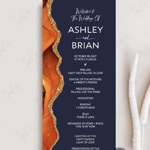 May include: A vertical wedding program card featuring a dark navy blue background with a textured burnt orange and gold glitter agate-style border. The text reads: Welcome to The Wedding Of ASHLEY and BRIAN, OCTOBER 18, 2027, ST PETE, FLORIDA, and ceremony details.