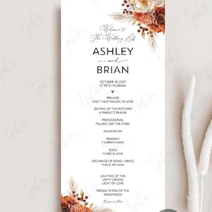 May include: A vertical wedding program card featuring a white background with floral arrangements in shades of orange, rust, and cream at the top and bottom. The text includes the names Ashley and Brian, the date October 18, 2027, and the ceremony order.