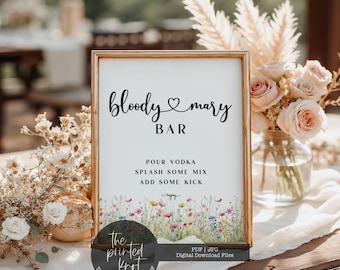 May include: A framed sign with the text "bloody mary BAR" in black script. Below, the sign reads "POUR VODKA, SPLASH SOME MIX, ADD SOME KICK." The bottom of the sign features a watercolor floral design. The sign is in a gold frame.