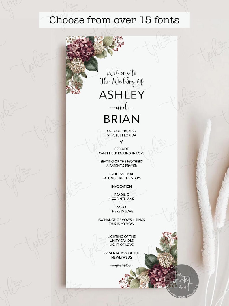 May include: A vertical wedding program card featuring a white background with floral arrangements of burgundy and cream hydrangeas in the top left and bottom right corners. The text reads Welcome to The Wedding Of ASHLEY and BRIAN, October 18, 2027, St Pete, Florida, and lists the ceremony order including prelude, processional, invocation, reading, solo, exchange of vows, unity candle, and presentation.