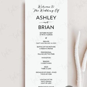 May include: A vertical white wedding program card featuring black text that reads Welcome To The Wedding Of ASHLEY and BRIAN, October 18, 2027, St Pete, Florida, and a detailed order of ceremony including prelude, processional, and vows.