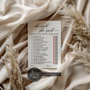 May include: A white card with the text "he said she said" in elegant script. The card features a list of statements with circles for marking answers, and is designed for a wedding or bridal shower game. The card is surrounded by decorative elements.