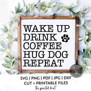 Könnte beinhalten: Ein Holzschild mit dem Text "WAKE UP DRINK COFFEE HUG DOG REPEAT" in Schwarz. Eine Pfotenabdruck-Grafik ist enthalten. Das Schild ist von Grün umgeben.