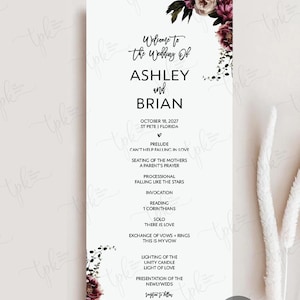 May include: A vertical wedding program card featuring black text on a white background, adorned with dark purple and cream floral illustrations at the top and bottom corners. The text lists the wedding of Ashley and Brian on October 18, 2027.