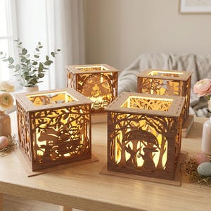 May include: Four wooden, illuminated lanterns with intricate cut-out designs. Each lantern features a square shape with detailed forest and Easter-themed scenes. The warm glow of the lights shines through the cut-outs, creating a cozy ambiance. The lanterns sit on a wooden table.