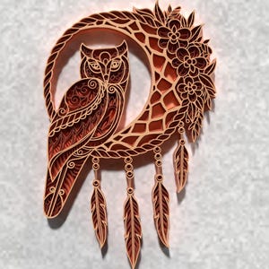 May include: A layered wood art piece featuring an owl perched on a crescent moon. The owl and moon are intricately detailed with floral and feather accents. The color palette is warm, with shades of brown and orange.
