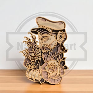 May include: Wooden layered art piece depicting a bearded sailor with a cap, holding a smoking pipe, and a rose. The artwork is in shades of brown and tan, with intricate details and a nautical theme.