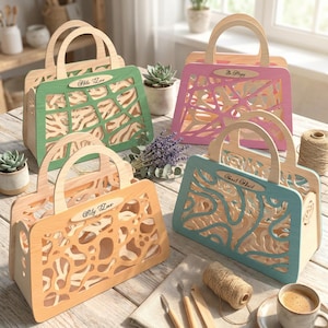 Op de afbeelding: Vier houten handtassen in pastelkleuren, elk met een uniek uitgesneden ontwerp en een handvat. De tassen zijn voorzien van opschriften als "My Love" en "Be Happy". De tassen staan op een houten tafel.