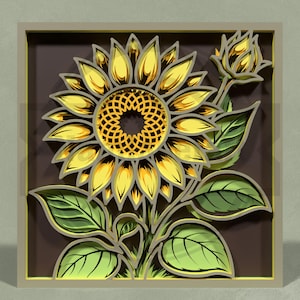 May include: A layered paper art piece featuring a sunflower with yellow petals and a detailed center. The artwork includes green leaves and a bud, all set within a square frame with a brown background.