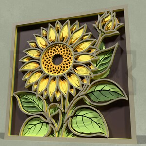Puede incluir: Una obra de arte de girasol en capas con una flor amarilla y dorada, hojas verdes y un fondo marr&oacute;n. El girasol est&aacute; en plena floraci&oacute;n con p&eacute;talos detallados y un centro texturizado. La obra de arte est&aacute; enmarcada en un borde marr&oacute;n claro.