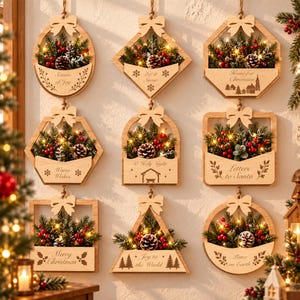 May include: Nine wooden wall-hanging ornaments in various geometric shapes, each featuring a bow at the top, evergreen branches, red berries, pinecones, and warm LED lights. Each piece displays unique engraved text like Season of Joy and Merry Christmas.