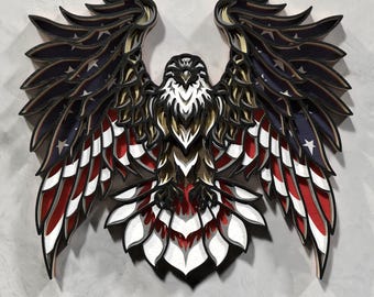 May include: A layered wooden eagle sculpture with outstretched wings, featuring the American flag's colors and stars. The eagle's body is brown and white, with red, white, and blue wings. The artwork is mounted on a light gray surface.