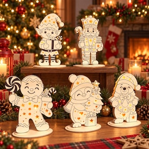 May include: Five light-up wooden Christmas ornaments featuring an elf, a nutcracker, a gingerbread person with a lollipop, a penguin holding a tree, and a bear with a wreath. Each figure has cut-out star and heart shapes that glow with warm light.