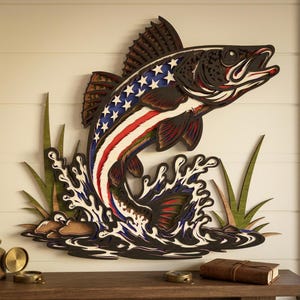 May include: A wooden wall art piece depicting a fish leaping out of water. The fish is painted with the American flag design, featuring stars and stripes. The artwork includes water splashes and green grass.