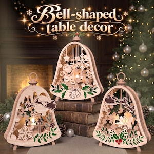 Op de afbeelding: Drie klokvormige houten tafeldecoraties met gedetailleerde lasergesneden ontwerpen van de Kerstman, rendieren, sneeuwvlokken en hulstbladeren. Elk stuk bevat een klein lichtje en de tekst Bell-shaped table decor.