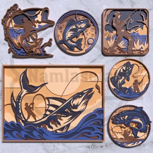 Può includere: Una collezione di opere d'arte in legno a strati con scene di pesca. I pezzi raffigurano pescatori, pesci e acqua in tonalità di marrone, blu e beige. Varie forme, tra cui un rettangolo, cerchi e un quadrato.