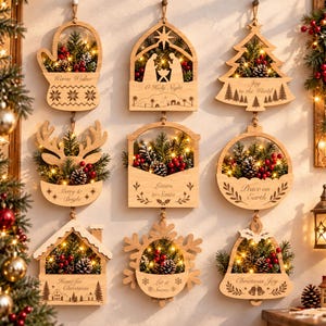 Pode incluir: Nove ornamentos suspensos de madeira clara com várias formas natalinas, incluindo uma luva, presépio, árvore, rena, envelope, esfera, casa, floco de neve e sino, preenchidos com ramos de pinheiro, bagas vermelhas e luzes.