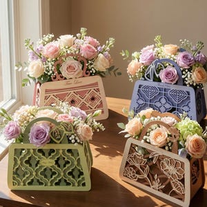 Op de afbeelding: Vier bloemstukken in handtasvormige containers. De containers zijn roze, blauw, groen en crème, met uitgesneden patronen. Ze zijn gevuld met rozen en andere bloemen. De roze container heeft de tekst "True Love".