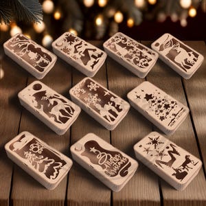 Op de afbeelding: Een verzameling rechthoekige houten dozen met ingewikkelde lasergesneden kerstontwerpen. Elke doos heeft een andere feestelijke scène, waaronder sneeuwvlokken, rendieren en kerstbomen. De woorden "Merry Christmas" zijn zichtbaar op één doos.