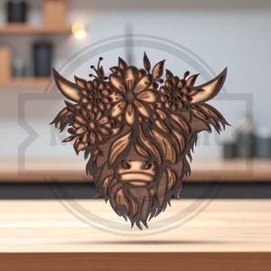 Puede incluir: Cabeza de vaca de las Tierras Altas de madera con corona floral. La talla de madera en capas presenta texturas detalladas y un acabado marr&oacute;n natural. Los cuernos y el pelaje de la vaca est&aacute;n intrincadamente tallados, con flores adornando la cabeza.