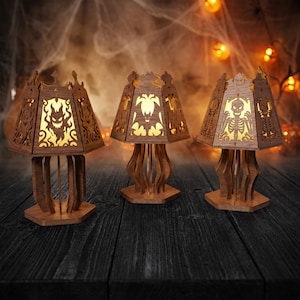 May include: Three wooden lamps with hexagonal bases and cut-out designs. The left lamp features a ghost, the center lamp shows a bat, and the right lamp displays a skeleton. Each lamp emits a warm yellow light through the intricate wooden panels.