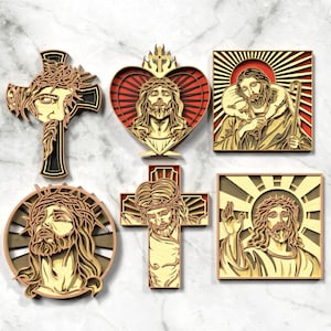 Pode incluir: Uma coleção de seis peças de arte de parede religiosa em madeira. As peças retratam Jesus em várias formas, incluindo numa cruz, dentro de um coração e com uma auréola. As obras de arte são em camadas com uma cor de madeira natural e detalhes em vermelho.
