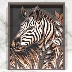 May include: A layered paper art piece featuring a zebra's head and foliage. The zebra has black and white stripes, with brown and tan accents. The artwork is framed in a gray shadow box, creating a 3D effect. The background is a dark gray.