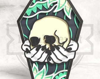 May include: A layered, decorative coffin-shaped design featuring a skull with stylized hands. The design incorporates a black frame, a dark gray background, and accents of light green and white, creating a gothic aesthetic.