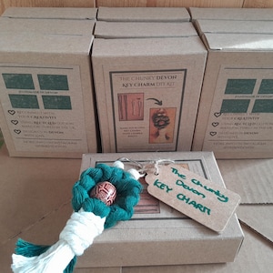 May include: Several brown cardboard boxes, each labelled "The Chunky Devon Key Charm DIY Kit." A handmade key charm with green and white accents and a tag reading "The Chunky Devon KEY CHARM" sits in front of the boxes.