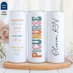 May include: Three white insulated tumblers with various designs. One tumbler has the words "GIGGLEATOR, little advocate, HEALER, tiny fixer, NURTURER, cuddle ninja" and a heart. Another says "PICUNURSE" in colorful letters. The third says "Olivia, RN".