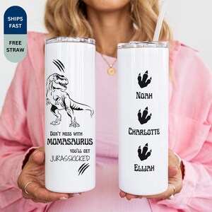 May include: Two white insulated tumblers. One features a black dinosaur graphic with the text "Don't mess with Momasaurus, you'll get Jurasskicked." The other has dinosaur footprint graphics with the names Noah, Charlotte, and Elijah.