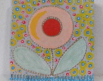 May include: Square canvas art depicting a stylized flower. The flower has a peach-coloured centre with a red dot and yellow crescent. Light green leaves and a blue picket fence border the bottom. The background is grey with yellow and blue circles.