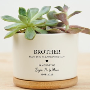 May include: A white ceramic planter with a succulent plant. The planter has the word "BROTHER" and the text "Always on my mind, forever in my heart" printed on it. It also includes "IN MEMORY OF Bryan H. Williams 1968-2026".