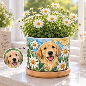 May include: A cylindrical ceramic planter featuring a colourful mosaic-style illustration of a golden retriever surrounded by white daisies. The planter sits on a circular wooden base and contains a live daisy plant with white petals and yellow centres.