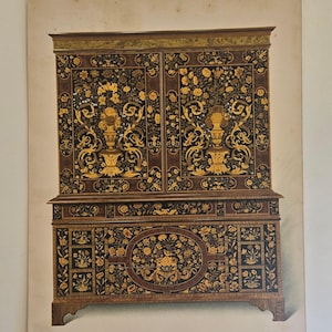 May include: An illustration of a detailed antique cabinet. The cabinet is dark brown with intricate gold floral and scrollwork designs. It features two doors on top and a lower section with a central oval design.