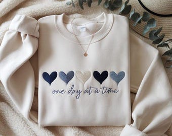 Broderad "en dag i taget"-design, söta hjärtan, design för medvetenhet om mental hälsa, inspirerande design, motiverande citat