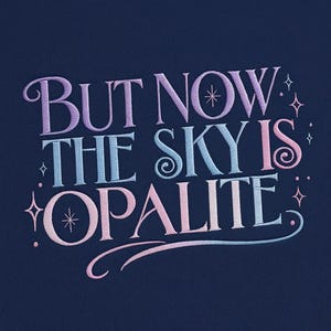 Puede incluir: Textil azul marino con texto bordado: "BUT NOW THE SKY IS OPALITE." El texto utiliza un degradado de colores pastel, morado, azul y rosa, con acentos de estrellas y remolinos.