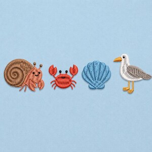 Op de afbeelding: Een set van vier geborduurde patches met een bruine heremietkreeft met een spiraalvormige schelp, een felrode krab met opgeheven scharen, een lichtblauwe schelp en een wit-grijze meeuw met een gele snavel en gele poten.
