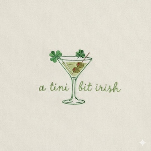 May include: Embroidered design of a martini glass with olives and shamrocks. The text "a tini bit irish" is written in a cursive font. The design is in shades of green and is on a cream-colored background.