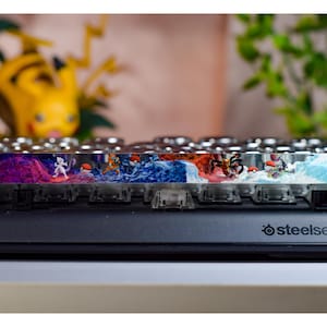 May include: A custom keyboard with a colorful, abstract design featuring a variety of characters. The keyboard is made by SteelSeries.