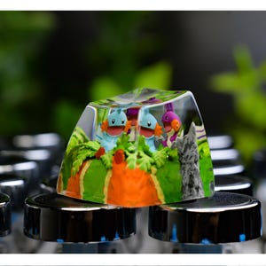 May include: A custom artisan keycap with a detailed design of cartoon characters in a colourful landscape. The clear keycap allows the design to be visible. The keycap is mounted on a keyboard.