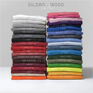 May include: A color chart for Gildan 18000 sweatshirts, featuring stacks of folded garments in various colors. The chart includes colors like white, black, red, navy, and orange, with the brand name and style number at the top.
