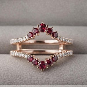 May include: Rose gold ring with a double band design. The top band features a row of small, sparkling white diamonds and a cluster of seven deep red gemstones. The bottom band also has a row of white diamonds and a cluster of red gemstones.
