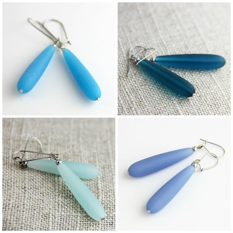 May include: Four pairs of dangle earrings with silver hooks and frosted glass teardrop-shaped beads. The earrings are in shades of blue, teal, and aqua.
