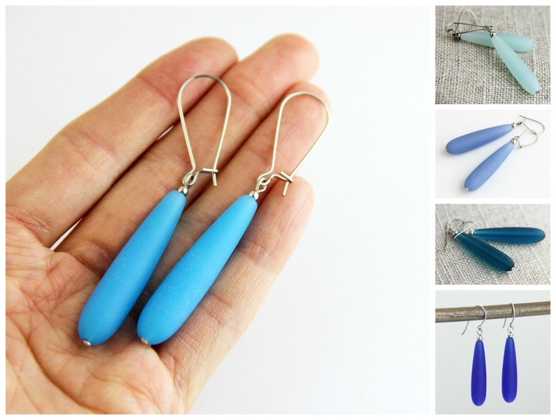 May include: A pair of dangle earrings with teardrop-shaped blue glass beads and silver hooks.