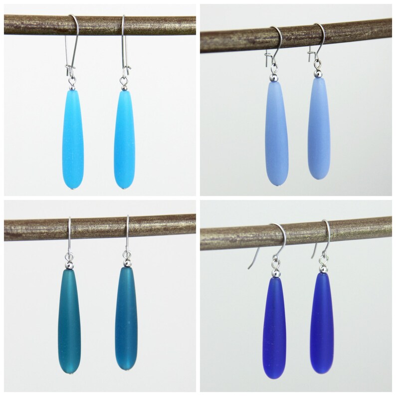 May include: Four pairs of teardrop-shaped glass earrings in various shades of blue. The earrings are silver and dangle from a hook.