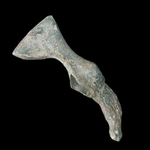 May include: A weathered bronze axe head with a curved handle and a triangular blade. The metal has a greenish-brown patina, suggesting age. The axe is set against a black background.