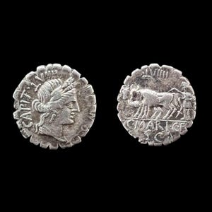 May include: A silver Roman denarius coin showing the obverse and reverse sides. The obverse features a profile of a deity with the text CAPIT. The reverse depicts a bull with the text C MAR I CF and LVIII, with a serrated edge design.